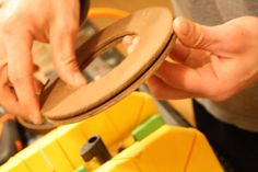 a person holding a piece of wood in front of a yellow box filled with other items