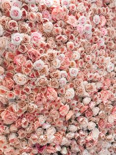 an arrangement of pink and white roses arranged in the shape of a heart on a wall