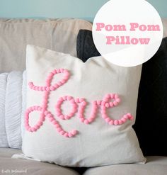 a white pillow with pink pom - pom beads on it sitting on a couch