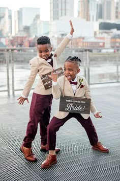 two young children dressed in formal wear posing for the camera with their hands up and one holding a sign that says bride