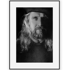 a black and white photo of a man with long hair, wearing a cowboy hat