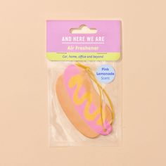 a pink and yellow hot dog shaped ornament on a card with an ad that says, and here we are air freshener