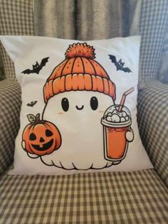 a white pillow with a pumpkin on it and a drink in front of the pillow