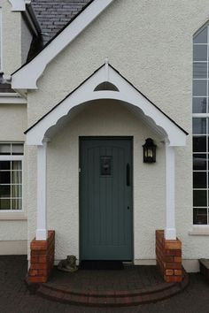 a white house with a green front door and brick steps leading up to the entrance