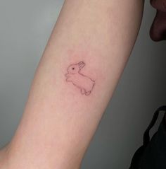 a small rabbit tattoo on the left inner arm and wrist, it appears to be pink