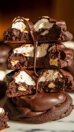 a stack of chocolate cookies with marshmallows and chocolate on top, drizzled with melted chocolate