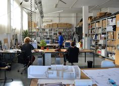 two people working in an office with desks and bookshelves