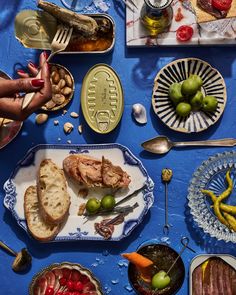 a blue table topped with plates and bowls filled with food