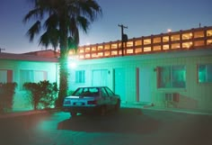 a car parked in front of a building with palm trees on the side of it