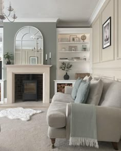 a living room filled with furniture and a fire place under a mirror on the wall