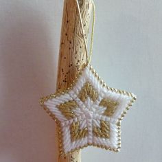 a white and gold star ornament hanging from a wooden stick