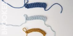 three crocheted items are shown on a white surface, one is blue and the other is yellow