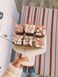 a person holding up a cake with marshmallows and candy canes on it