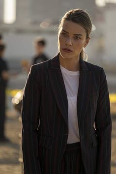 a woman in a pinstripe suit is looking at the camera while standing outside