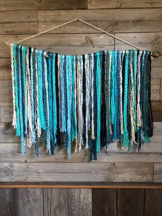 a wall hanging made out of yarn on a wooden board with wood planks in the background