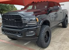 a large gray truck parked in front of a building with an umbrella over it's head