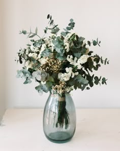 a vase filled with white flowers and greenery