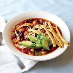 a white bowl filled with chili and french fries on top of a blue table cloth