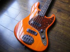 an orange electric bass guitar laying on the floor