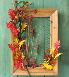 a wooden frame with fall leaves and flowers in it