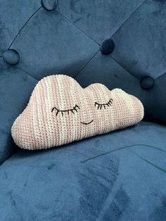 a cloud pillow with eyes drawn on it sitting on a blue velvet sofa cushion in the shape of a sleeping cloud