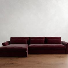 a red couch sitting on top of a hard wood floor next to a white wall