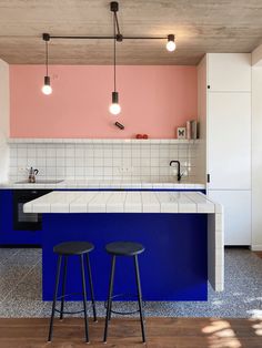 two stools sit in front of an island with blue and pink counter tops on it