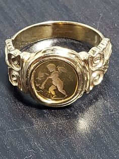 This stunning 18 karat yellow gold ring from Italy features an exquisite oval-shaped  Venetian glass measuring 9.0mm in width and 10mm in length. The stone is set in a beautiful bezel and the ring is size 6.25, with a band width of 4mm. The ring is also sizable and has an attractive signet style, with an intaglio featuring an angelic theme, perfect for any occasion. The gold metal purity is 18k and the base metal is gold, giving it an elegant and timeless look. This captivating ring is perfect for those who appreciate fine jewelry and would make a great addition to any collection. The ring comes with features like a single citrine gemstone, yellow gold metal, which makes it a unique piece. This ring is ideal for those who are looking for an exquisite jewelry piece with a touch of Italian c Italian Ring, Intaglio Jewelry, Vintage Jewelry Rings, Vintage Jewellery Rings, Glass Ring, Coin Jewelry, Glass Rings, Venetian Glass, Citrine Gemstone