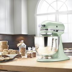 a green mixer sitting on top of a wooden counter next to cookies and crackers