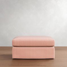 an upholstered footstool sitting on top of a wooden floor next to a wall