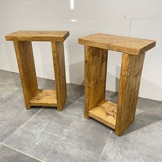 two wooden side tables sitting next to each other on top of a tile floor in front of a white wall