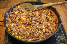 a skillet filled with chili and corn sitting on top of a stove next to a spatula