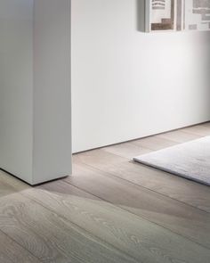 an empty room with white walls and wood flooring on the ground, in front of a door