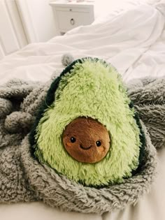 a stuffed animal that is laying down on a bed with a blanket over it's head