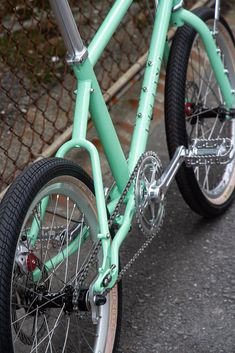 a green bicycle parked next to a chain link fence