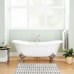 a white bath tub sitting on top of a hard wood floor next to a window