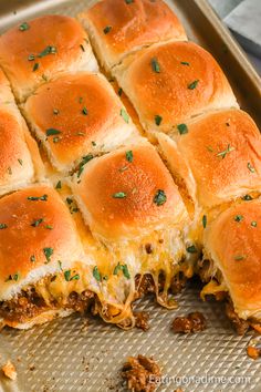 a bunch of sliders sitting on top of a pan covered in cheese and meat