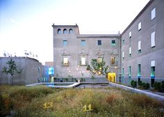 an empty courtyard in front of two buildings with plants growing out of the ground and windows