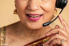 an older woman wearing a headset and holding her finger up to the side while smiling