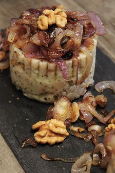 some food that is on top of a black plate with nuts and other things around it