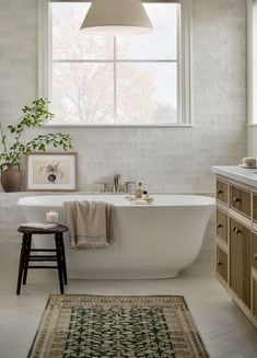 a white bath tub sitting under a window next to a rug