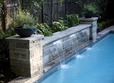 a pool with water running down it and plants growing on the edge next to it