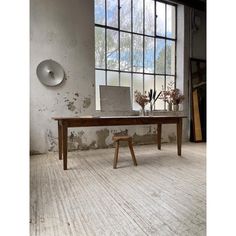 a wooden table sitting in front of a window next to a vase filled with flowers