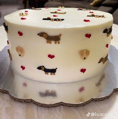 a white cake decorated with dogs and hearts