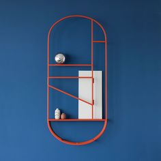 an orange shelf on the wall with two balls and a piece of paper next to it