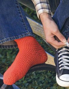 a man tying his shoes with red socks