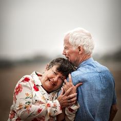 an older couple embracing each other in a field