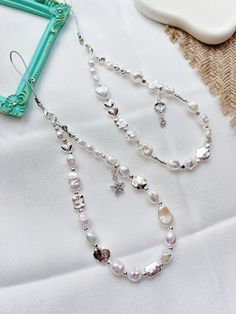 a white necklace with pearls on it and a star charm hanging from the end, next to a blue frame