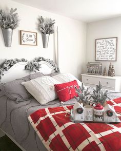 a bedroom decorated for christmas with red and white decorations on the bed, potted pine trees