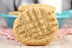 two peanut butter cookies sitting on top of a table next to a bowl of milk